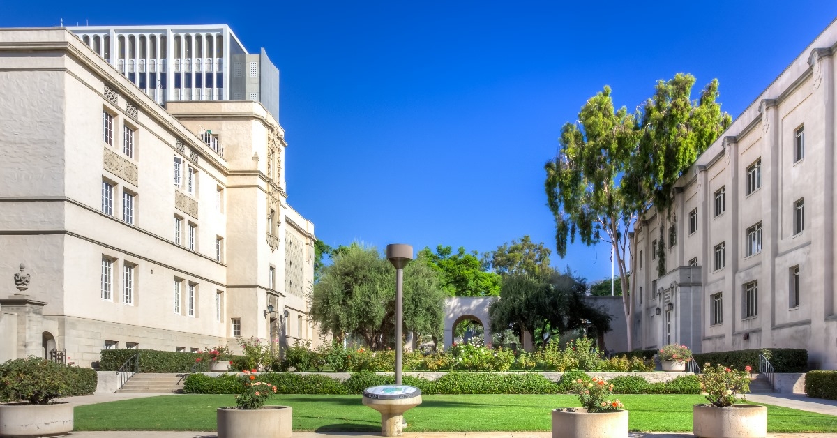 main entrance at caltech university with green gardens and whitewashed buildings on sunny day