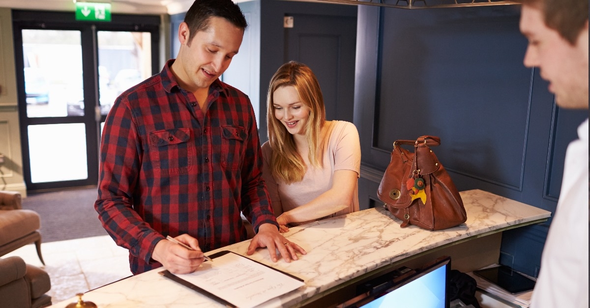 happy couple on vacation signing documents at reception before checking in at hotel