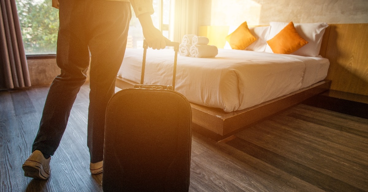 female tourist with luggage moving into hotel room with sunlight coming out of window