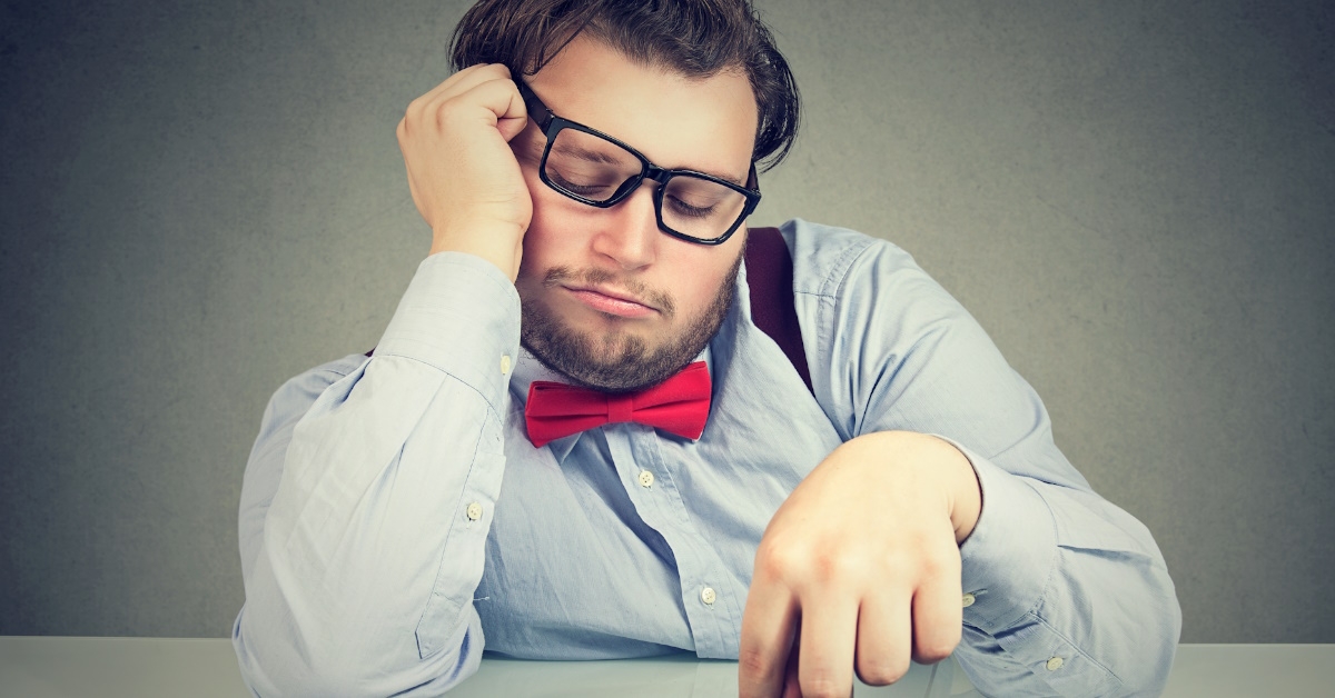 male employee sitting at table with keyboard procrastinating his work