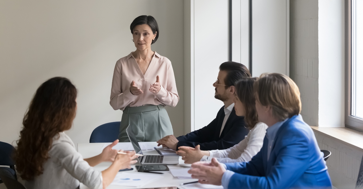 executive team listen to mature female CEO presenting