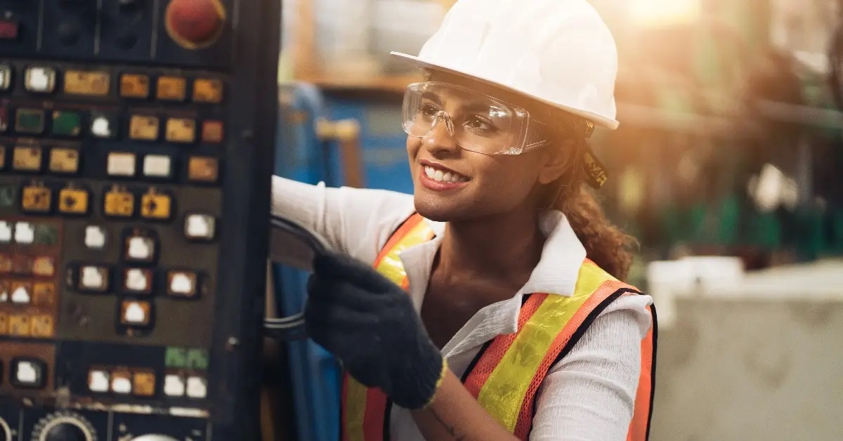 female engineering wearing white helmet monitering machinery at factory operating workshop.