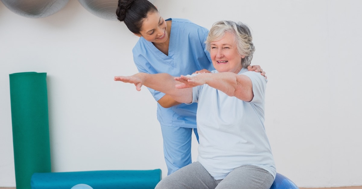 physiotherpist flexing arms of an old lady during a therapy session at her clinic