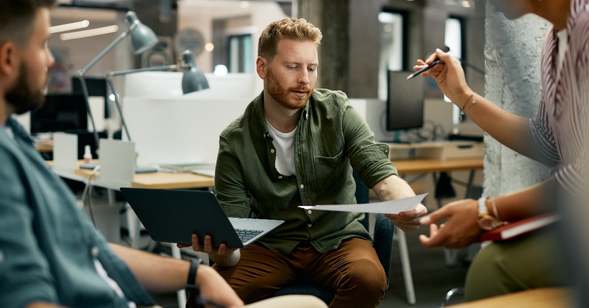 Confident financial advisor pointing at  laptop while discussing different options with senior woman in office
