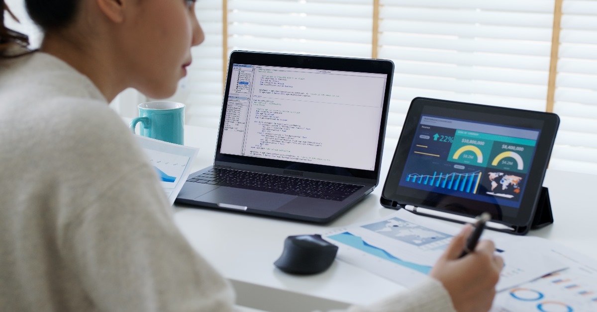 Back rear view of young asian woman running computer programs and analyzing outputs  while sitting in her cabin in office.