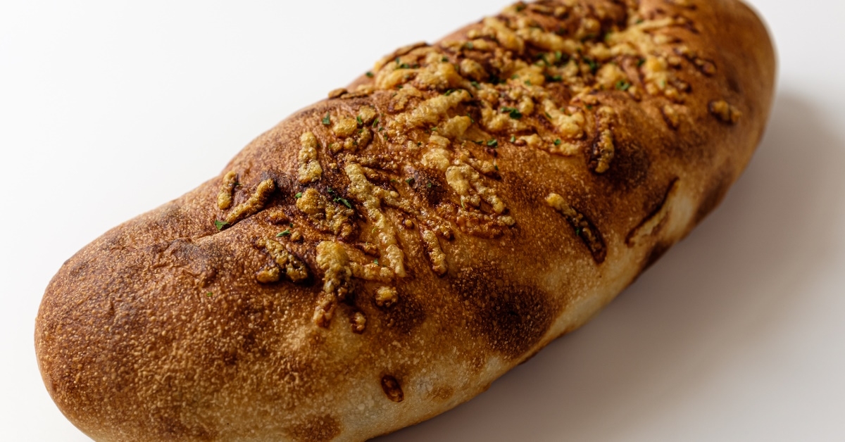 A delicious looking freshly baked bread with fine toppings on the top against plane white background.