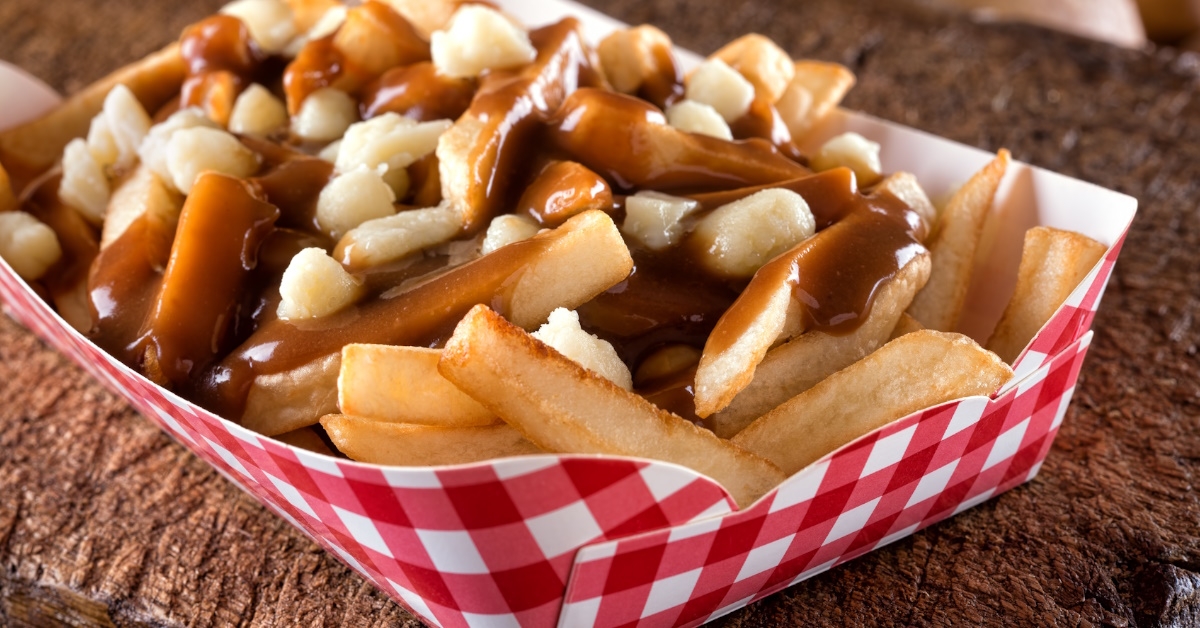 poutine made up of  french fries and cheese curds topped with a brown gravy to be taken away.