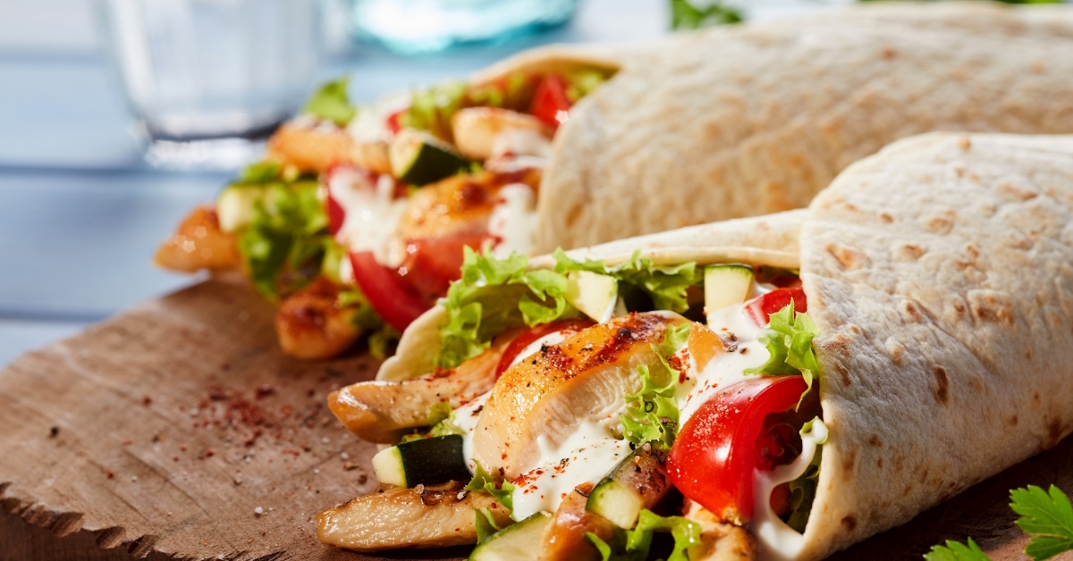 Tex-Mex tortilla wraps with creamy avocado and hearty black beans combine with Tex-Mex flavors served on wooden dish.