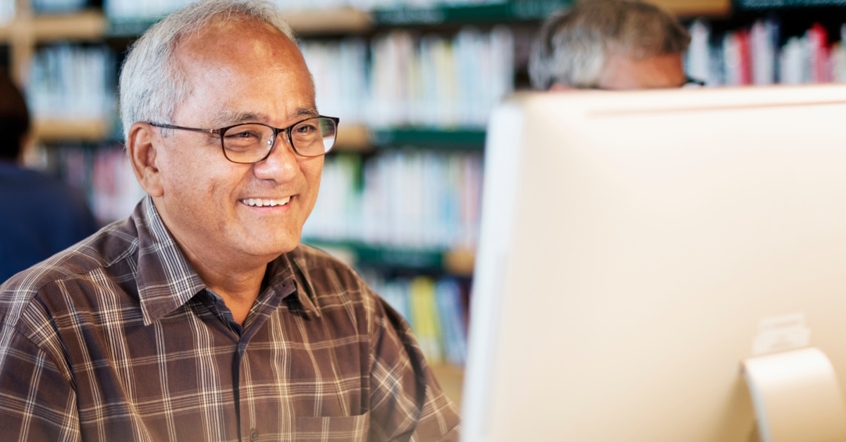 A senior citizen is utilizing a computer for socialization purposes at a public library.