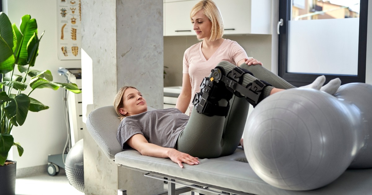 A young woman wearing orthosis to support her limbs is taking a physiotherapy session with her therapist at the clinic