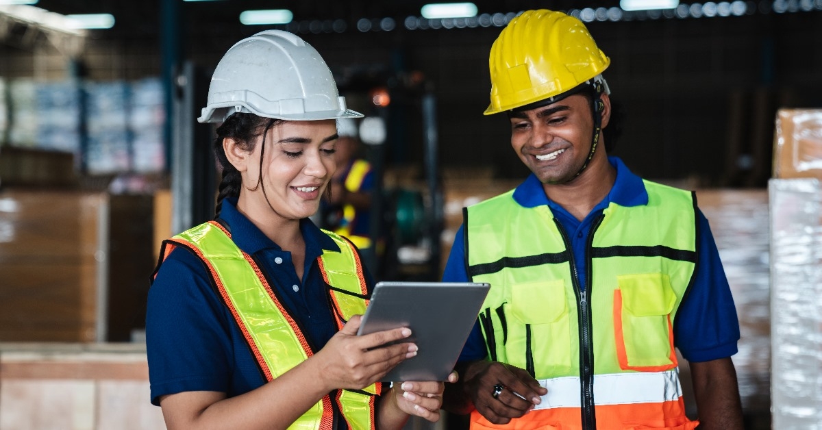 Warehouse workers checking work details on a tablet in the background industrial warehouse.