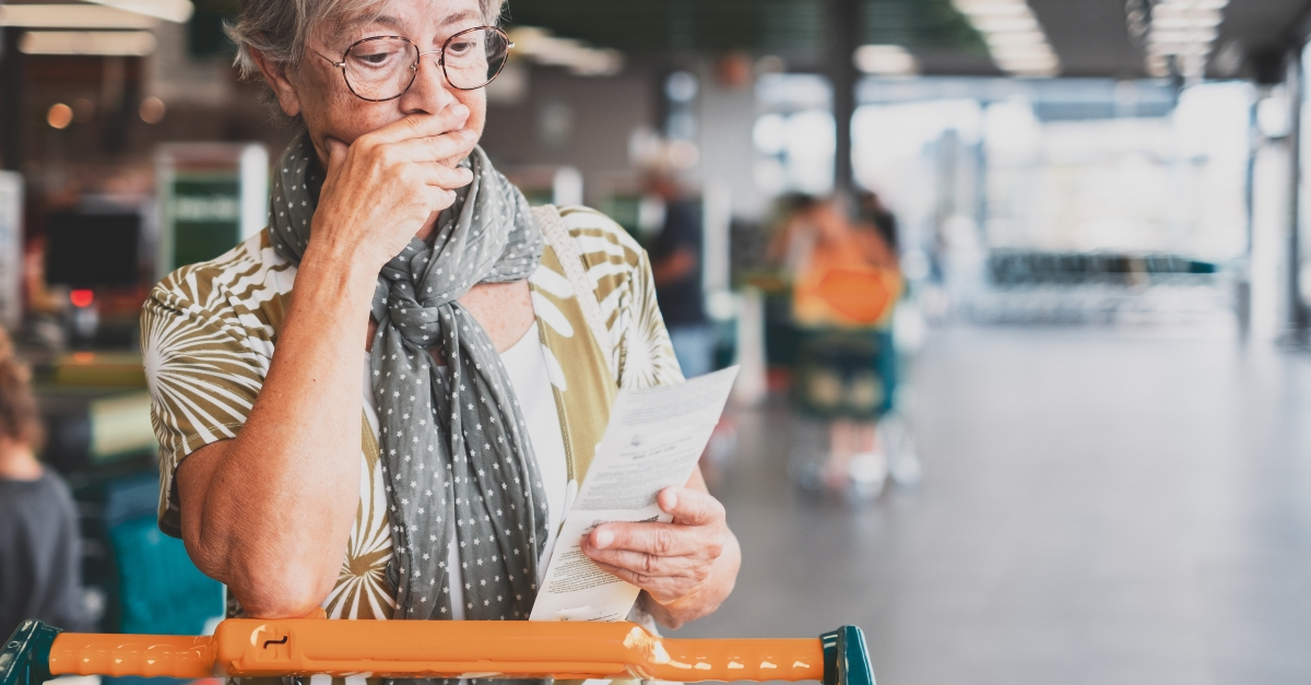 senior woman in the supermarket checks her grocery receipt