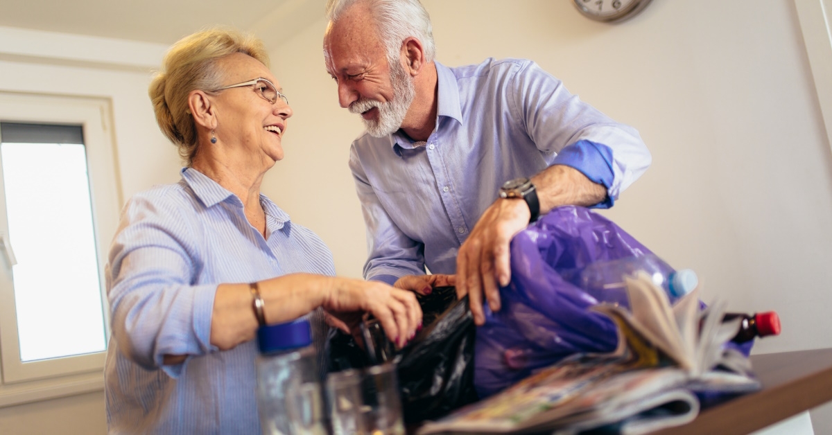 smiling senior couple recycling trash
