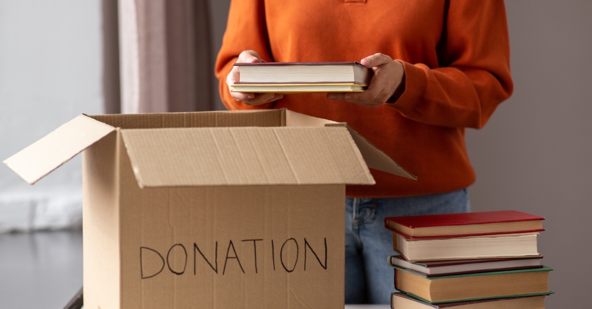 woman donating books in brown box