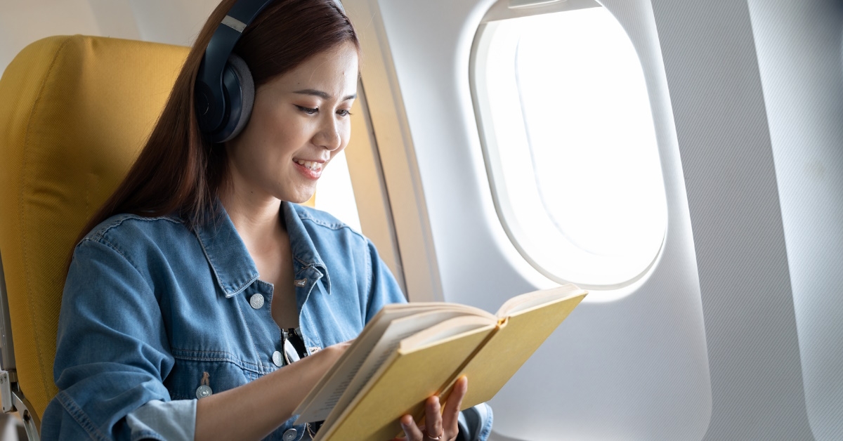 asian woman on airplane reading book