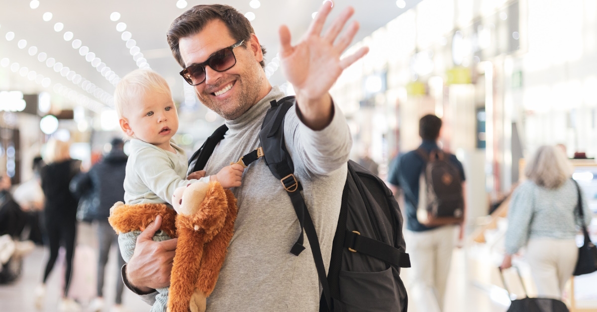 father with infant waving at airport