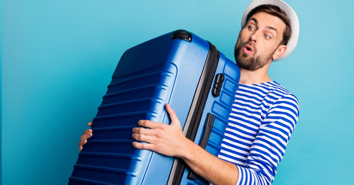 handsome man holding giant suitcase