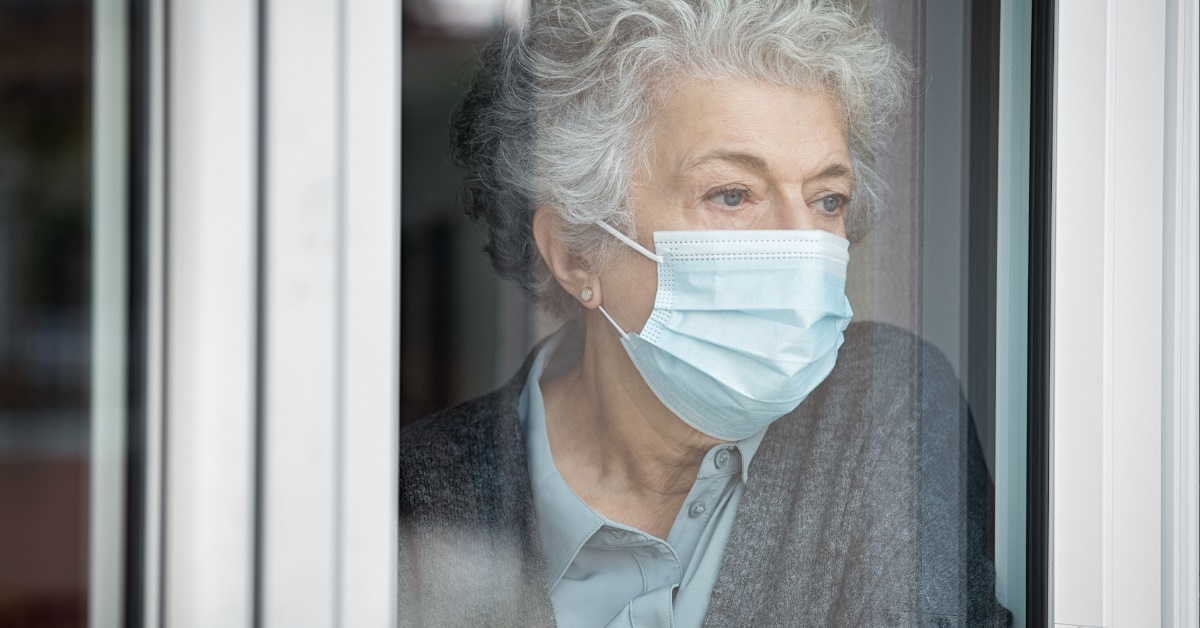 serious aged woman standing at window
