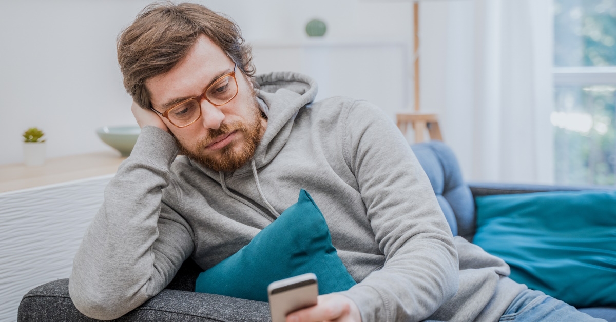 serious man using phone on couch