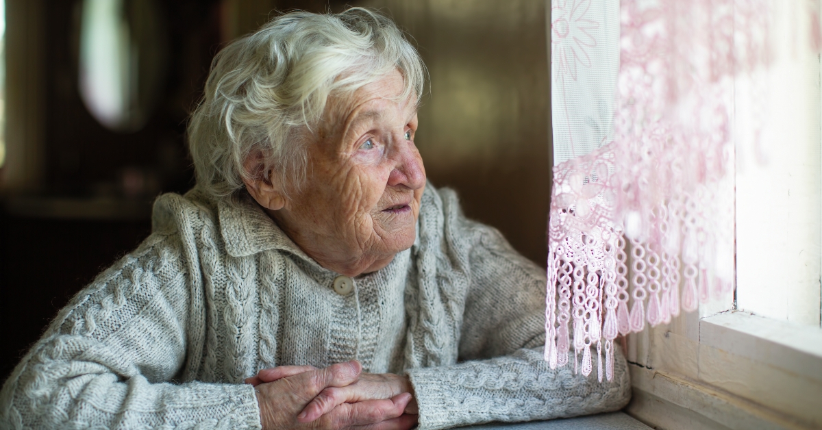elderly woman looks out the window