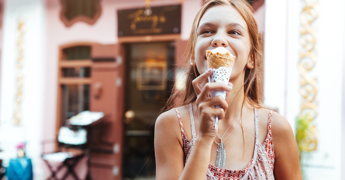 girl eating ice cream on city street.