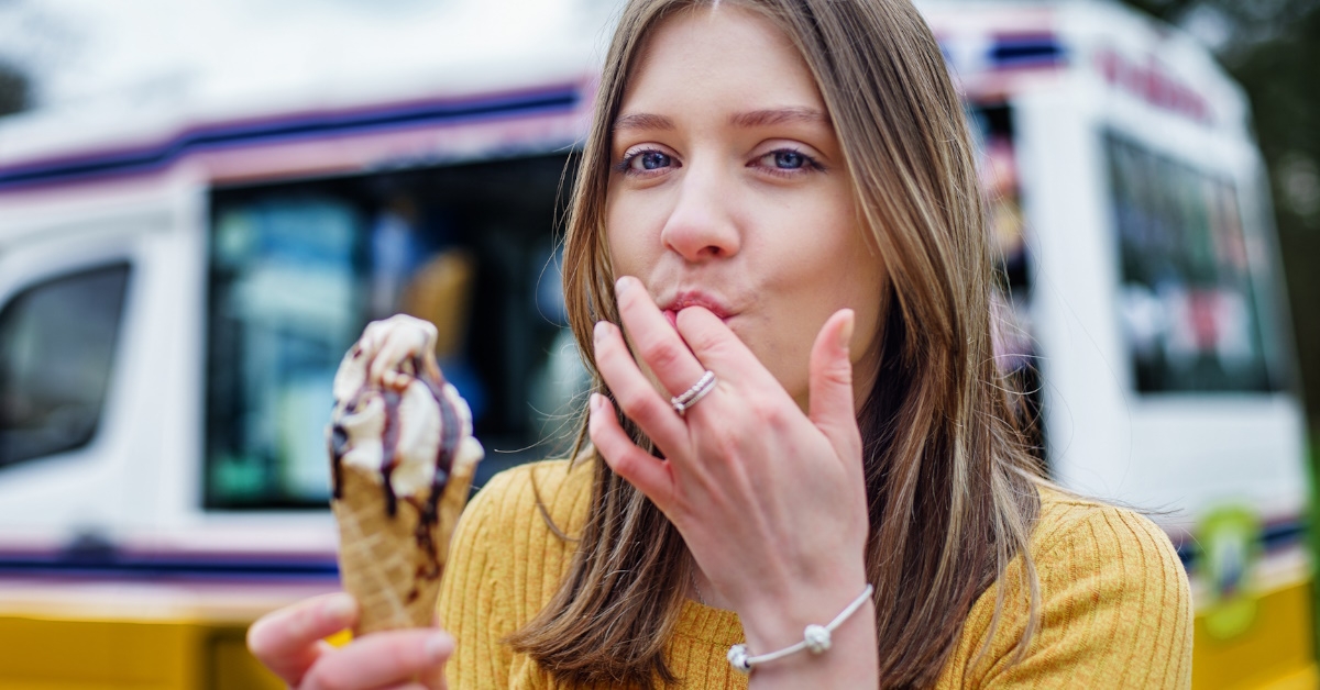 girl licking fingers while eating ice cream.