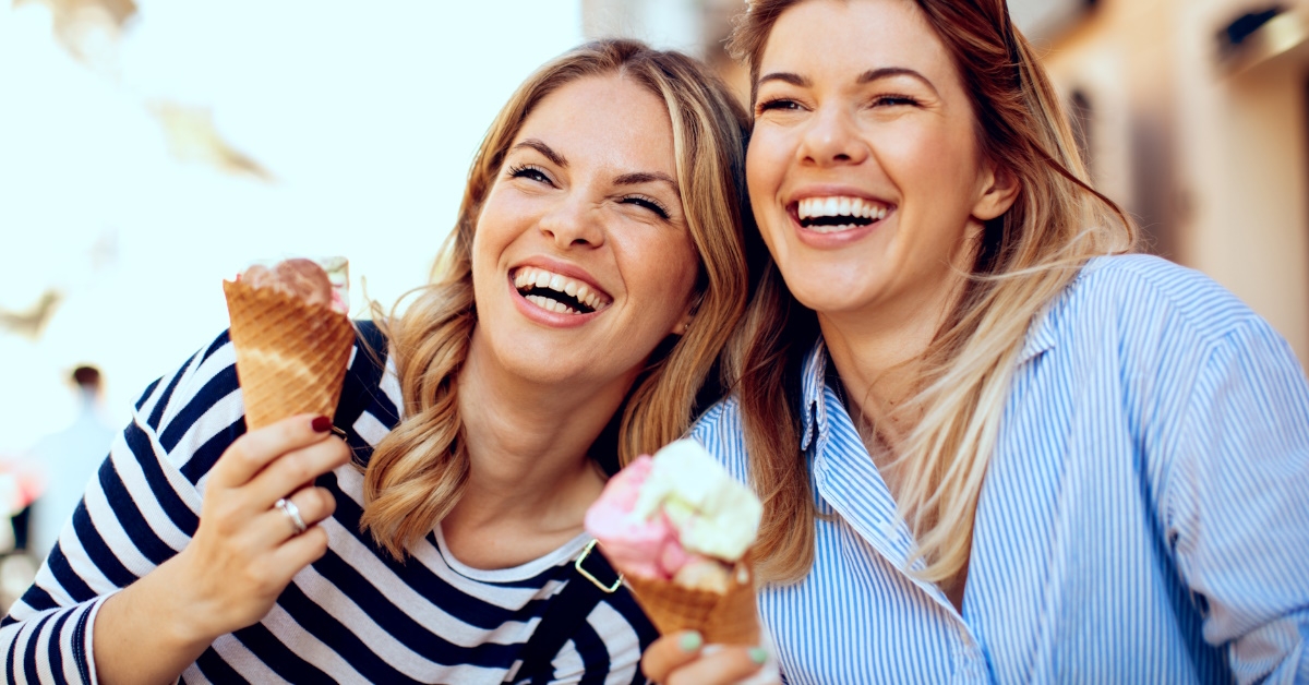 two women laughing and eating ice cream