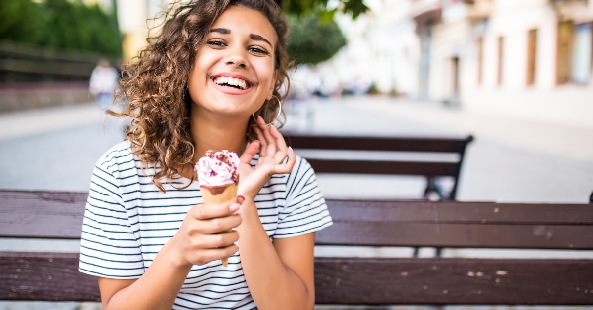 woman seated in park showing ice cream. 