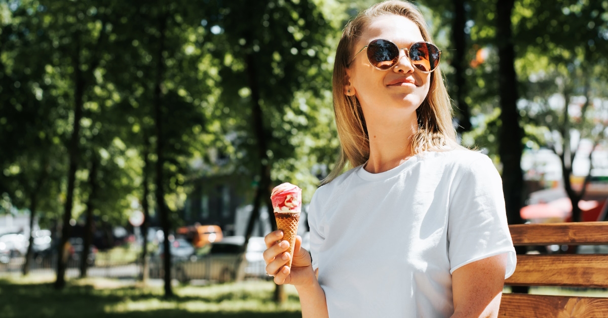 young woman holding ice cream in park.