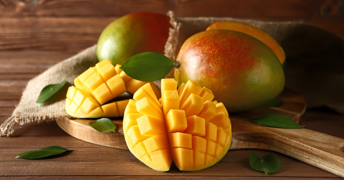 fresh mangoes on wooden board