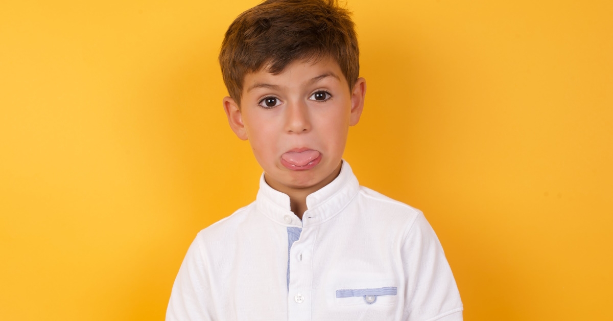 depressed young boy sticking out tongue