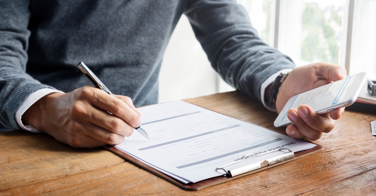 man writing insurance application