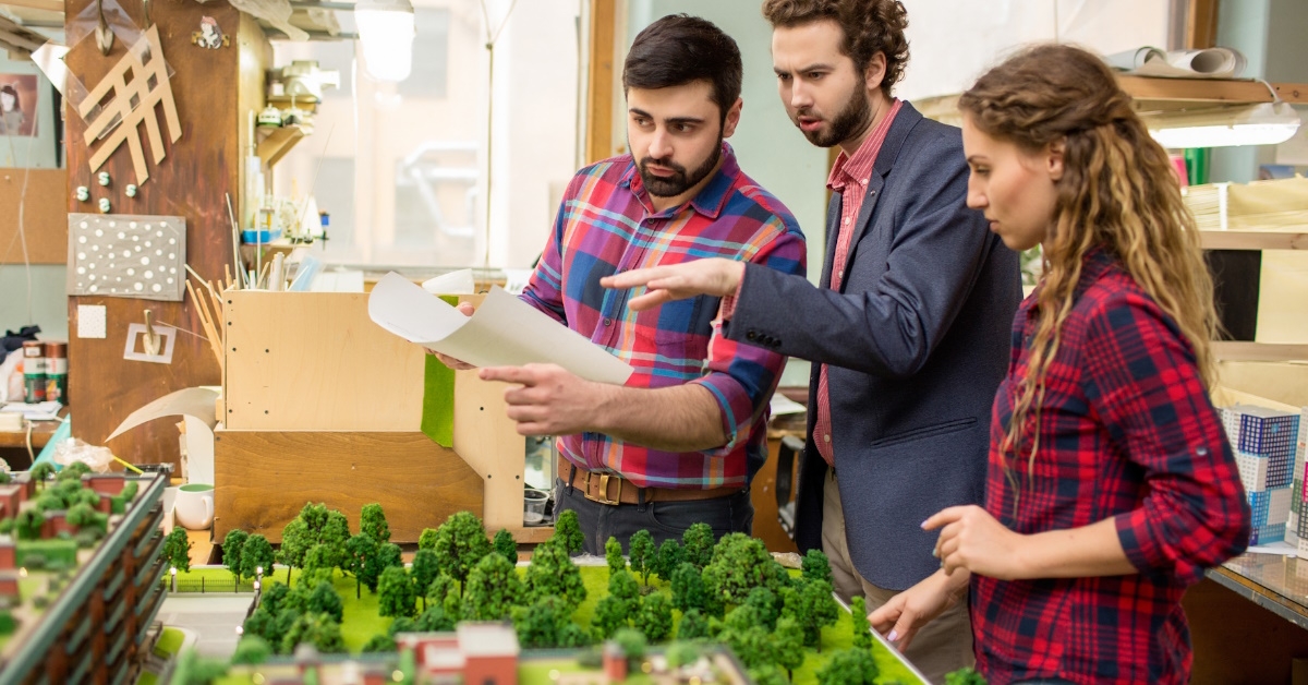landscape designers examine a model of city's layout.