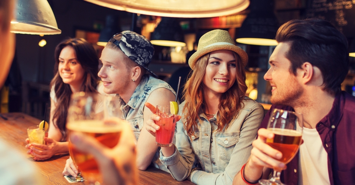 friends with drinks talking at bar