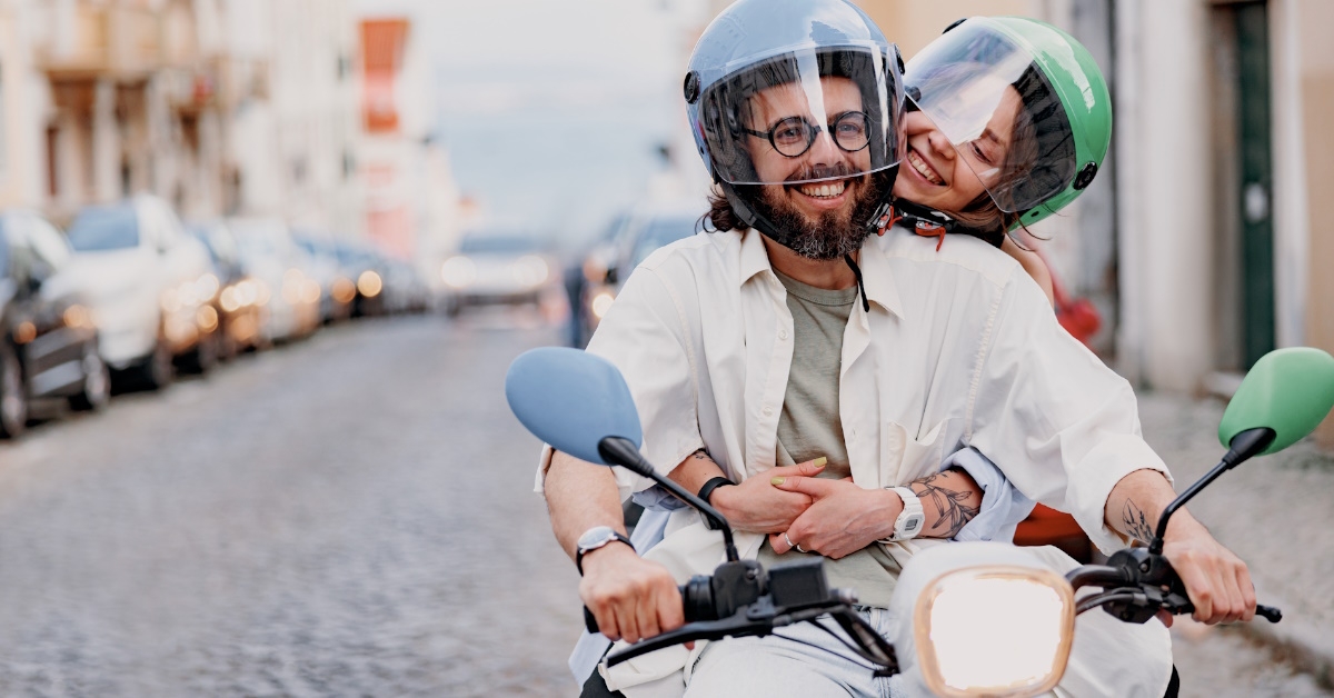 happy couple riding scooter while traveling