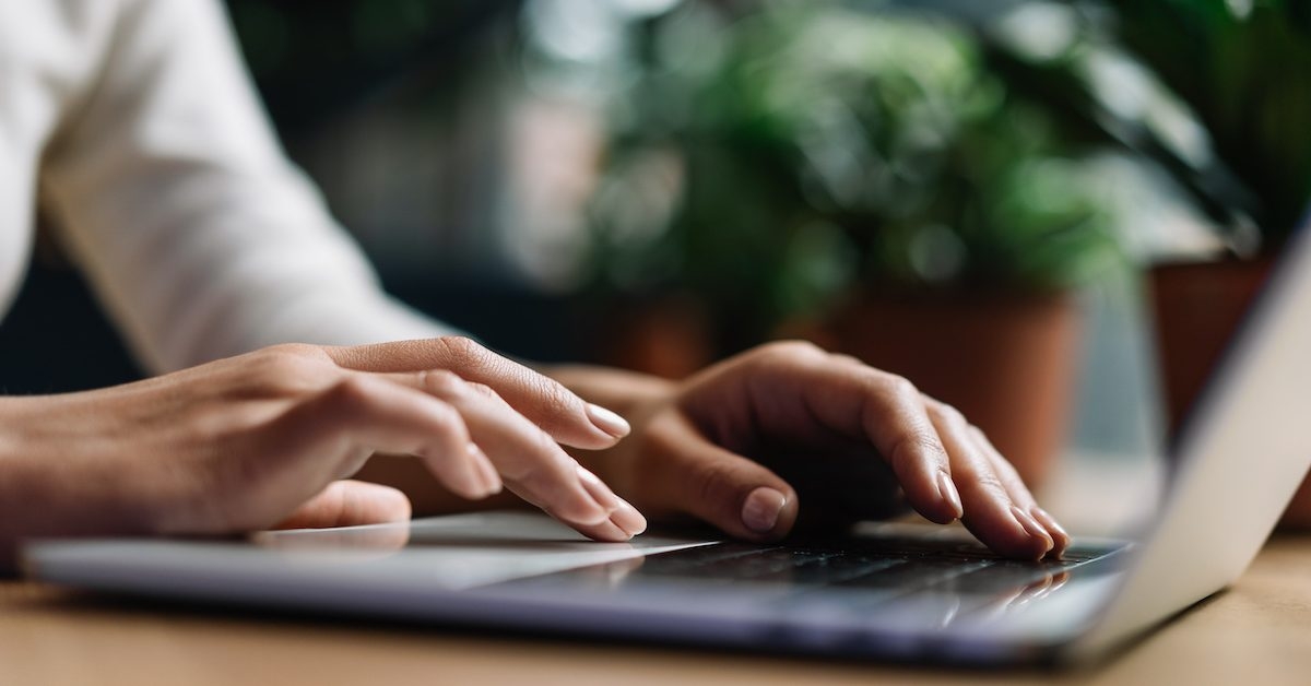 View of a person's hands typing on a laptop keyboard.