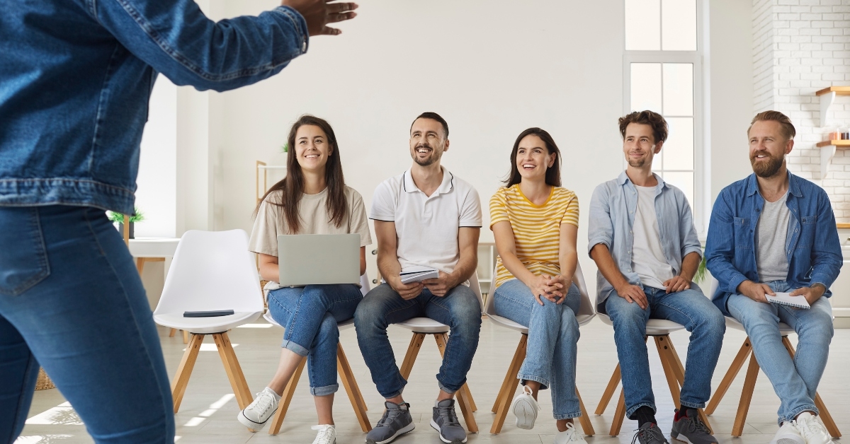 Group of happy men and women sitting in row on chairs