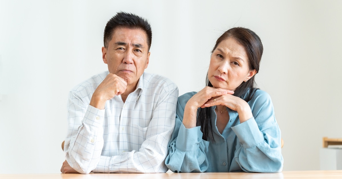 unhappy asian couple over white backdrop