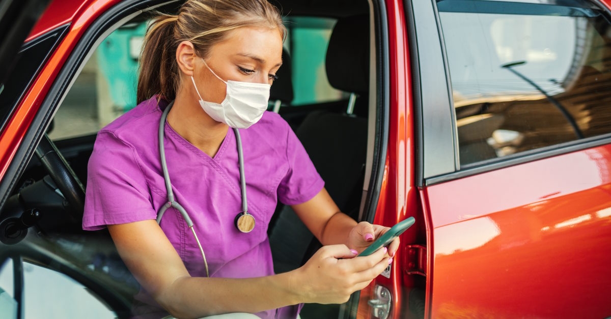 female doctor using phone in car