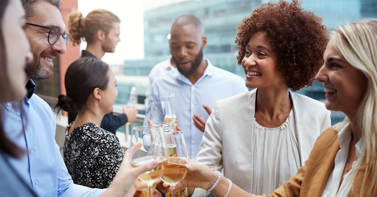 happy colleagues toasting wine after work