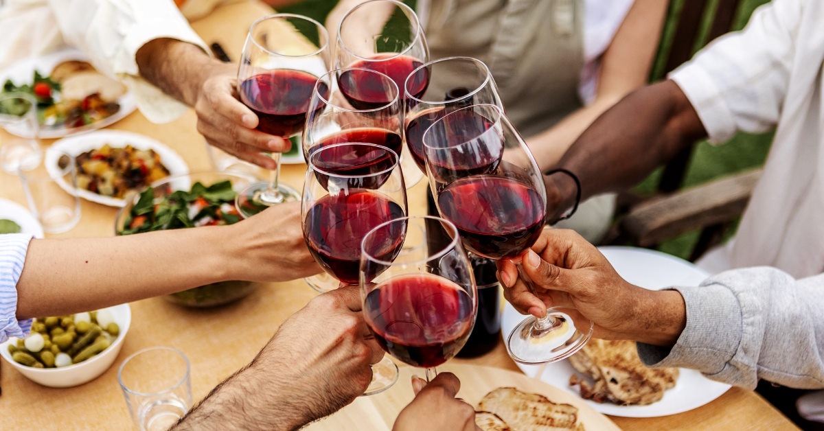 Friends toasting red wine glasses outdoors