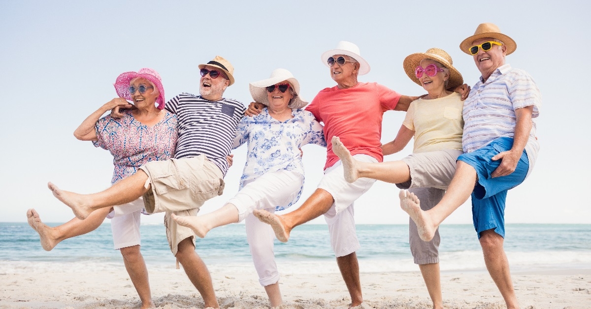 senior friends joyfully dancing on the beach.