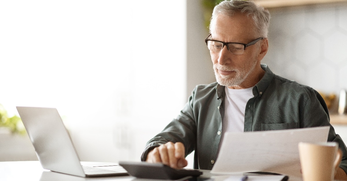 Elderly man computing taxes in his home.