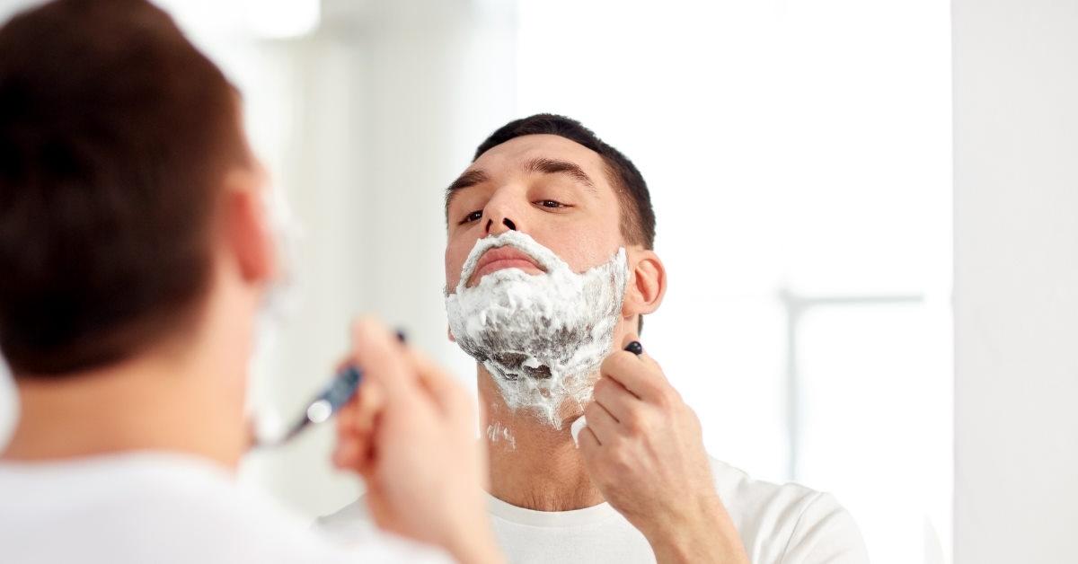 man shaving beard using razor