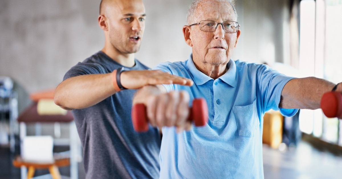 Physiotherapist helping a senior man with weights