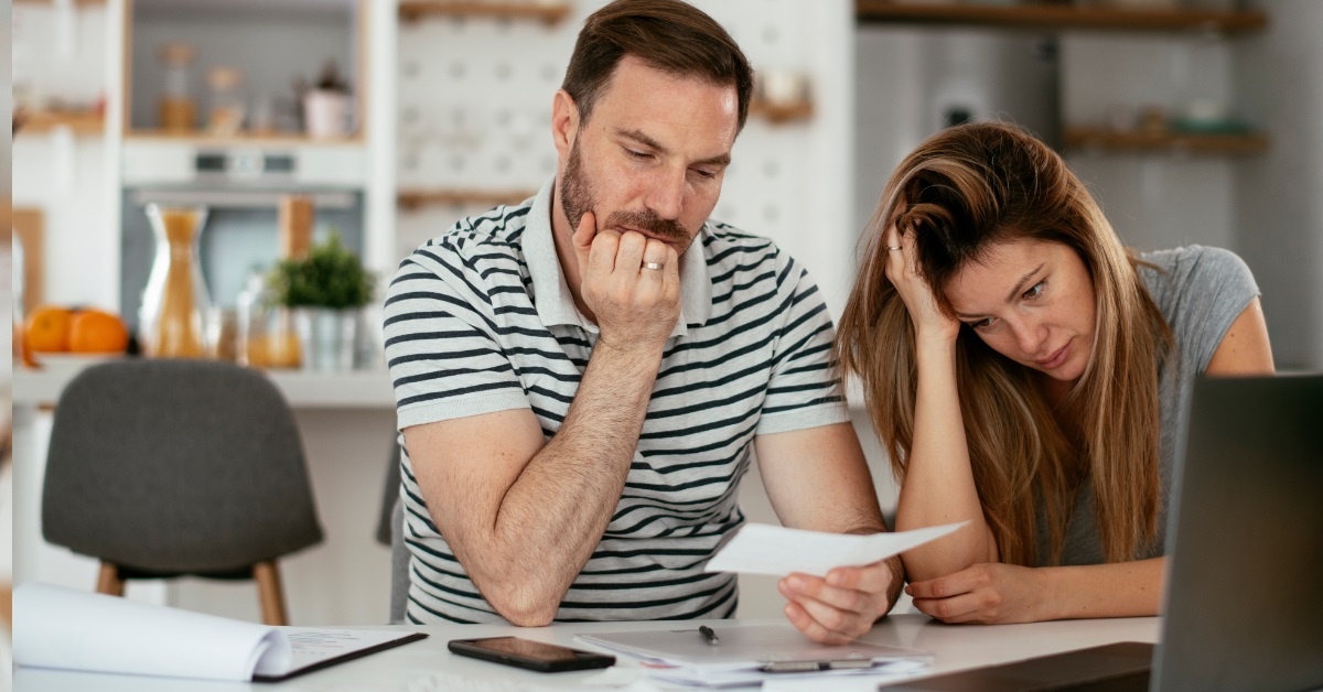 Sad couple reviewing bills at home
