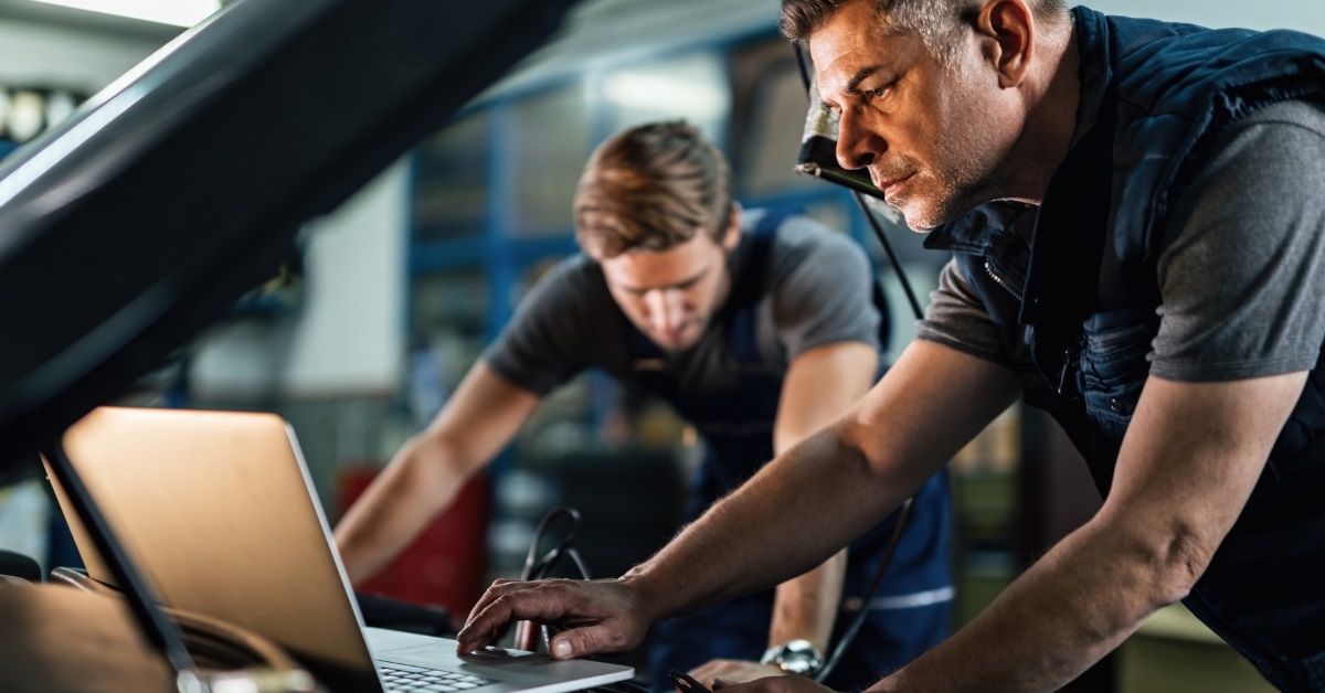 professional mechanics diagnosing car using laptop