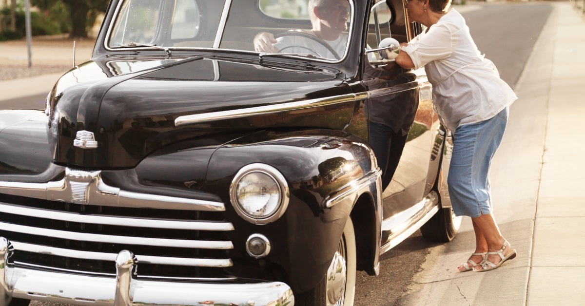 senior couple talking besides vintage car