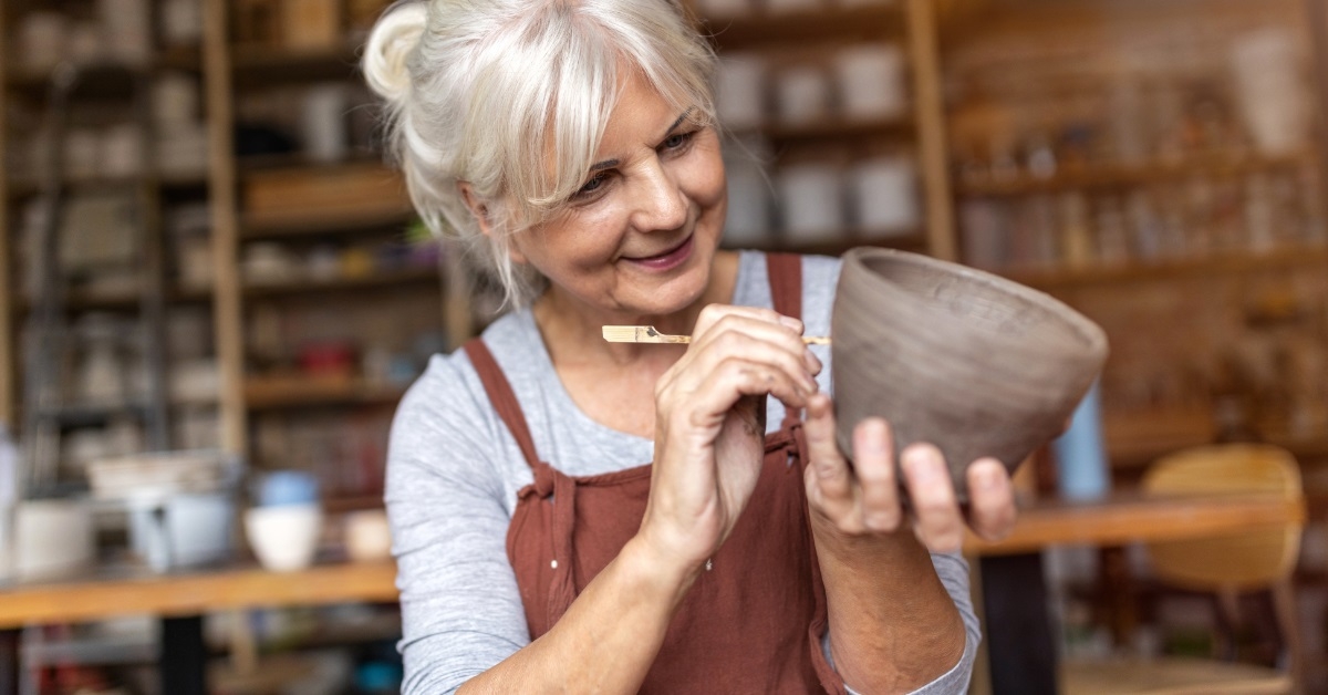 senior female artist painting ceramic pot