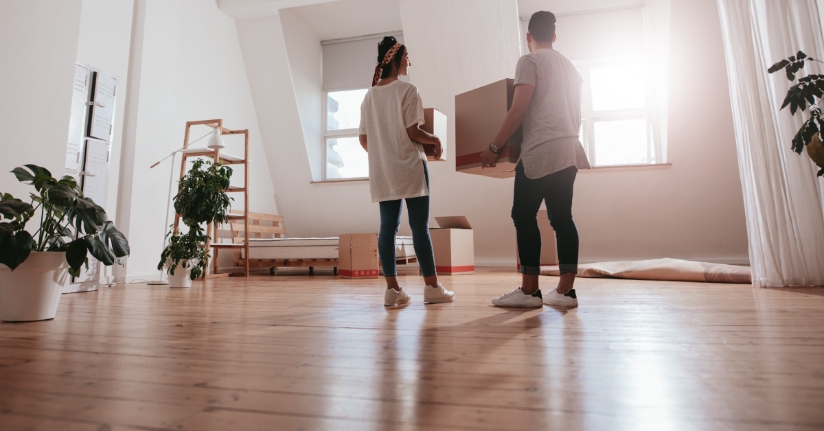 couple holding boxes in new house